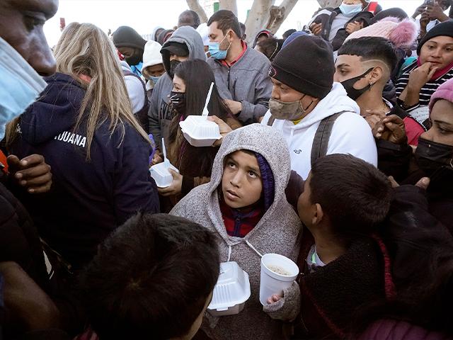 Asylum seekers receive food as they wait at the border in Tijuana, Mexico. (AP Photo/Gregory Bull)