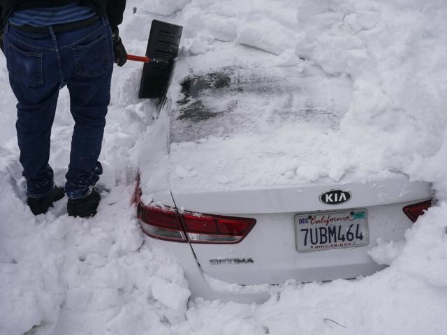 Kenny Rybak, 31, shovels snow that has engulfed his car in Running Springs, Calif. (AP Photo/Jae C. Hong)