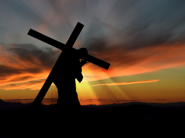 silhouette of a person carrying a cross