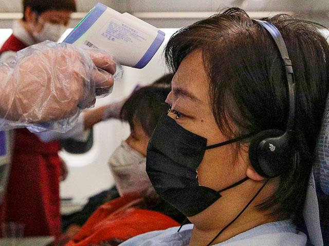 Stewardesses take temperatures of passengers as a preventive measure for the coronavirus on an Air China flight from Melbourne to Beijing (AP photo)