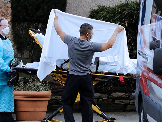In this Feb. 29, 2020, file photo, a person is taken by a stretcher to an ambulance from a nursing facility where more than 50 people were sick and being tested for COVID-19 virus, in Kirkland, Wash.  (AP Photo/Elaine Thompson)