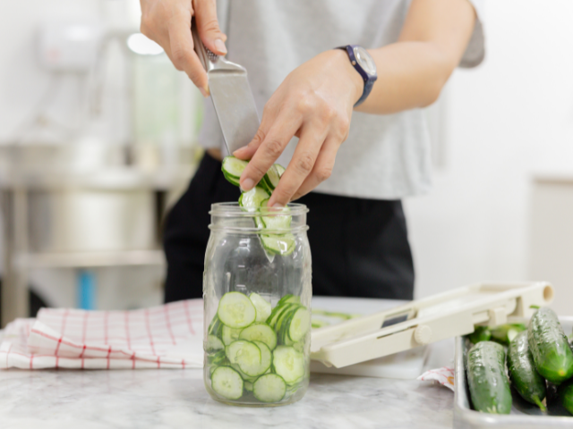 woman canning pickles in a mason jar