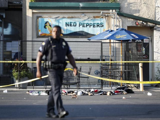 Shoes are piled outside the scene of a mass shooting including Ned Peppers bar, Sunday, Aug. 4, 2019, in Dayton, Ohio (AP Photo/John Minchillo)