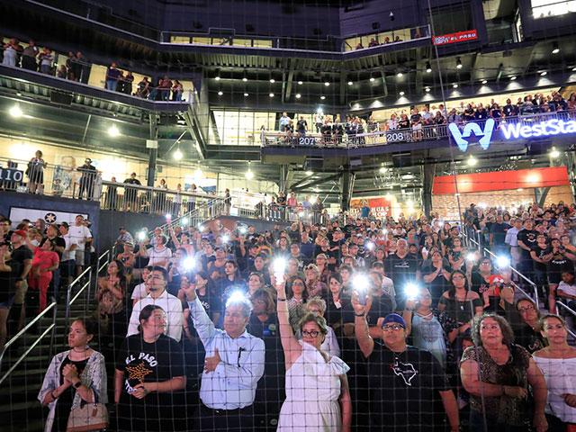 People hold up their cellphones as the names of the victims of the Aug. 3 mass shooting are read during a memorial service, Wednesday, Aug. 14, 2019, at Southwest University Park, in El Paso, Texas. (AP Photo/Jorge Salgado)