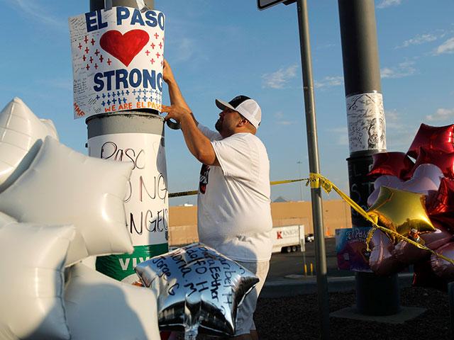 In this Aug. 6, 2019 file photo, a man hangs up an &quot;El Paso Strong&quot; sign at a makeshift memorial at the scene of a mass shooting at a shopping complex in El Paso, Texas.  (AP Photo/John Locher, File)