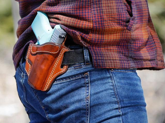 A man carries a firearm in his holster. 