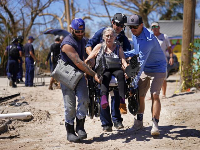 Rescuers help evacuate Suzanne Tomlinson, a resident who rode out Hurricane Ian on Pine Island in Florida