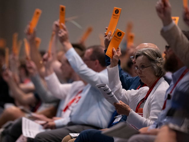 Los mensajeros levantan sus boletas en apoyo de una moción presentada para votación durante la reunión anual de la Convención Bautista del Sur el martes 11 de junio de 2024 en Indianápolis. (Foto AP/Doug McSchooler)