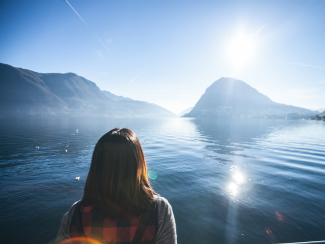woman gazing at light above mountain lake