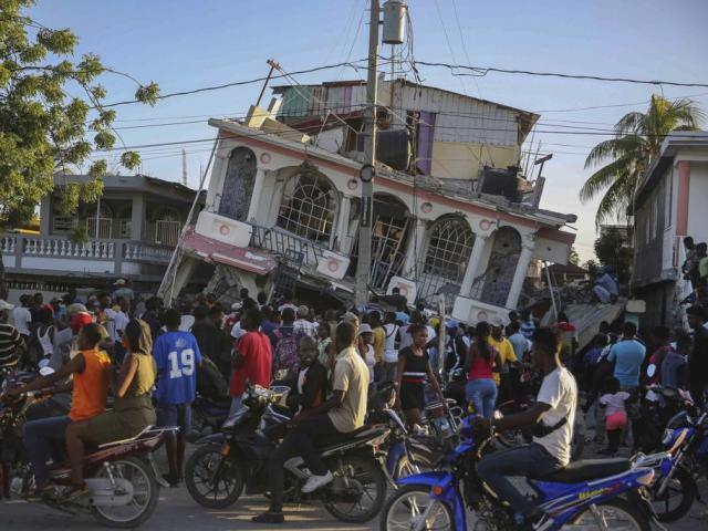 People gather outside the Petit Pas Hotel, destroyed by the earthquake in Les Cayes, Haiti, Saturday, Aug. 14, 2021. (AP Photo/Joseph Odelyn)