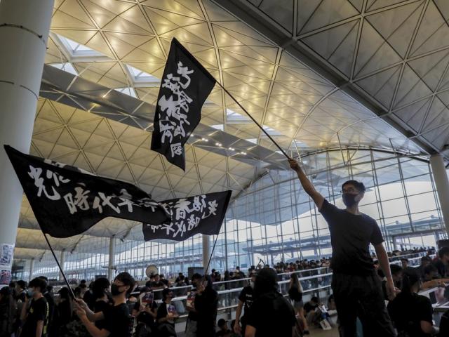 Protesters wave flags at the Hong Kong International Airport, Monday, Aug. 12, 2019 (AP Photo/Kin Cheung)
