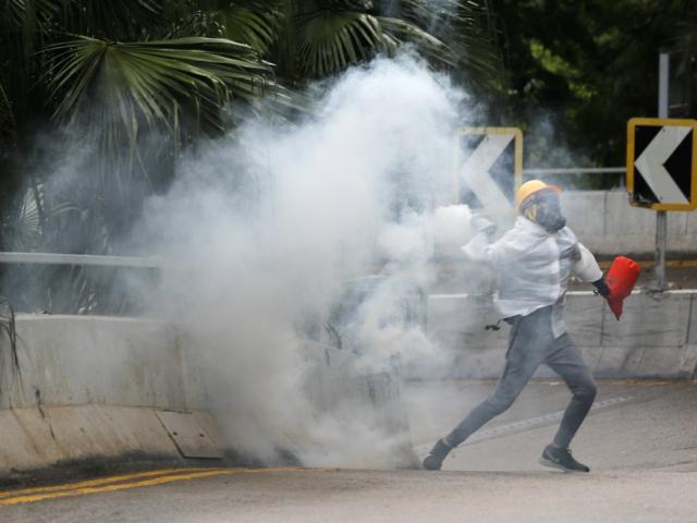 Protesters throw back tear gas at police in Hong Kong, Sunday, Oct. 6, 2019 (AP Photo/Vincent Thian)