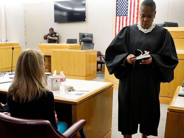 State District Judge Tammy Kemp opens a Bible to John 3:16 before giving it to former Dallas Police Officer Amber Guyger, left, before Guyger left for jail, Wednesday, Oct. 2, 2019, in Dallas. (Tom Fox/The Dallas Morning News via AP, Pool)