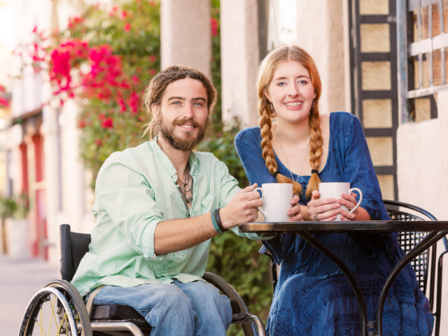 man in a wheelchair at a cafe with his wife