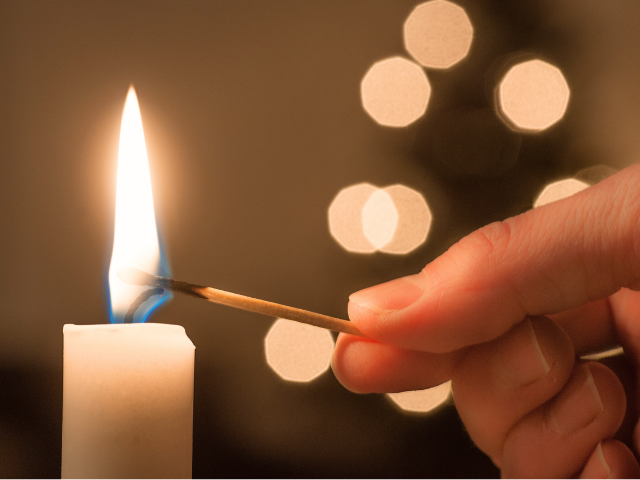 person lighting a candle with a match