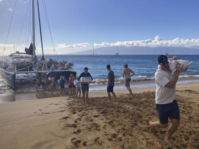 Volunteers who sailed from Maalaea Bay, Maui, form an assembly line on Kaanapali Beach to unload donations from a boat. (AP Photo/Rick Bowmer)