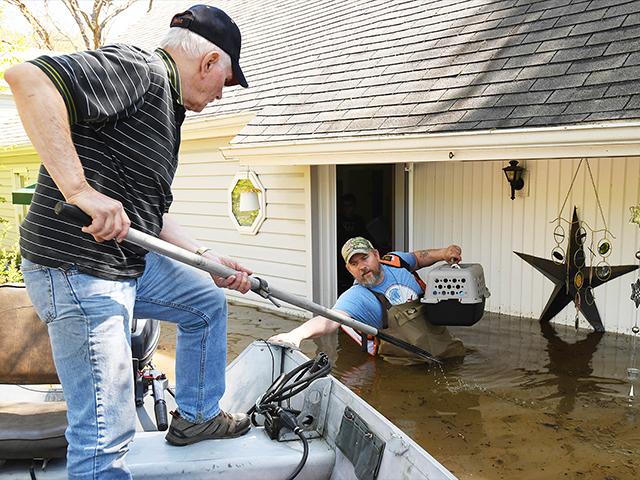 Don Thomas of Saginaw pulls his boat up to his son Jason Thomas who went back to his house near W. Signet in Midland to retrieve his family&#039;s cats. Flooding along the Tittabawassee River in Mich. on May 20, 2020. (Daniel Mears/ The Detroit News via AP)