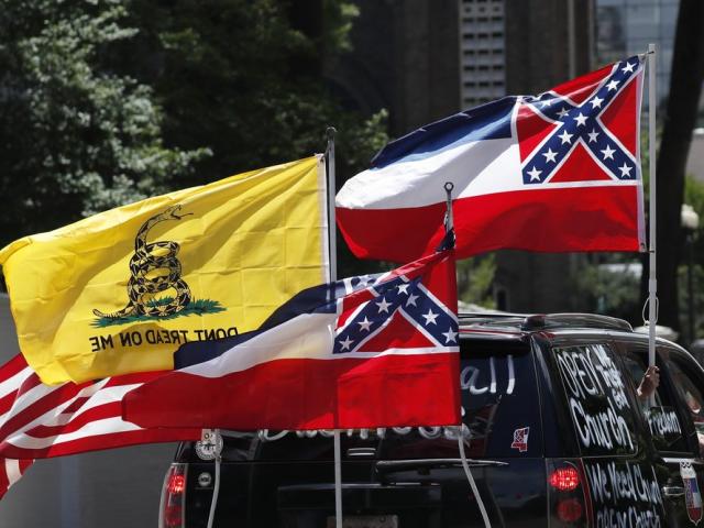 In this April 25, 2020 photo, Mississippi state flags are positioned on a vehicle amid an arrangement with the American flag (AP Photo/Rogelio V. Solis)