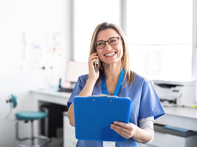 smiling nurse talking on phone and holding a tablet