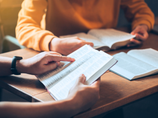 group Bible study with open Bibles and one person pointing to a Scripture