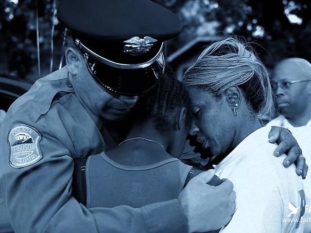 A police officer prays with grieving citizens.