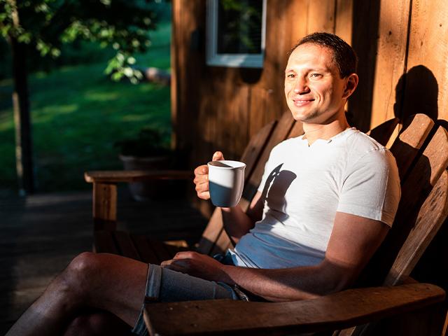 man sitting in a chair on the front porch having coffee