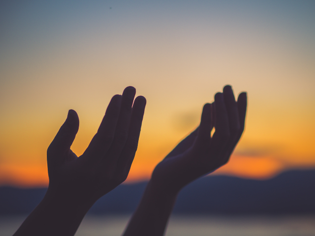 hands lifted in praise at sunset