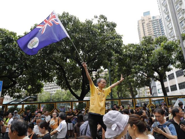 A man waves a colonial British-era Hong Kong flag as people gather at a public park ahead of a planned demonstration in Hong Kong, Saturday, Aug. 3, 2019.(AP Photo/Vincent Thian)