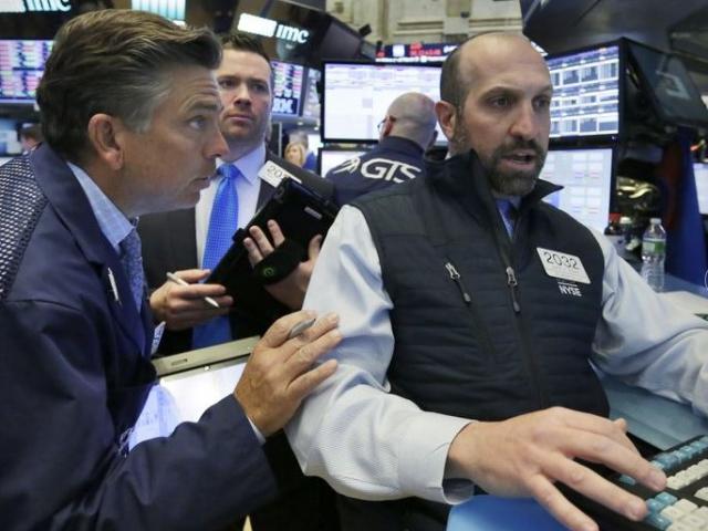Specialist James Denario, right, works with traders on the floor of the New York Stock Exchange.