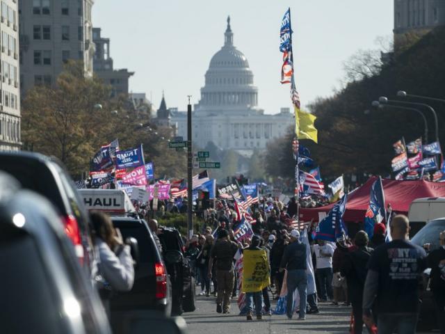 A motorcade carrying President Donald Trump drives by a group of supporters participating in a rally near the White House, Saturday, Nov. 14, 2020, in Washington. (AP Photo/Evan Vucci)