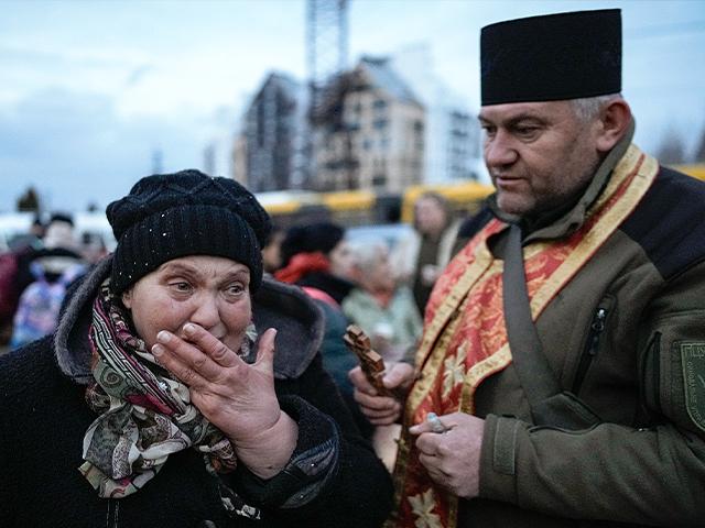 A military priest tries to comfort a crying woman who was evacuated from Irpin, at a triage point in Kyiv, Ukraine (AP Photo/Vadim Ghirda)