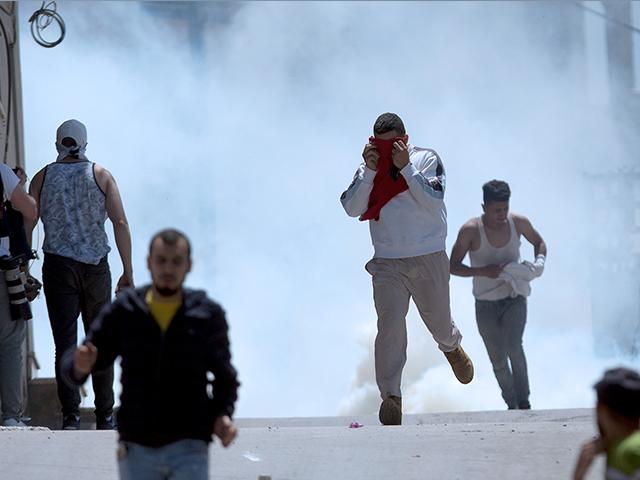 AP Photo: Palestinians run away from tear gas fired by Israeli soldiers during clashes after a soldier was killed
