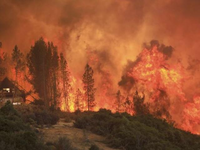 Flames from a wildfire advance up a ridge, towering over a home that eventually burned on Thursday near Lakeport, Calif. (Kent Porter/The Press Democrat via AP) 