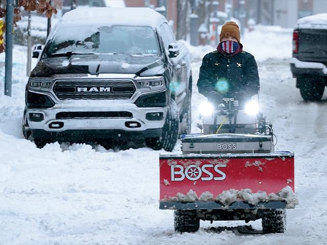 A worker drives a sidewalk snow plow down the middle of a street on Pittsburgh&#039;s Northside on Monday, Jan. 17, 2022. (AP Photo/Gene J. Puskar)