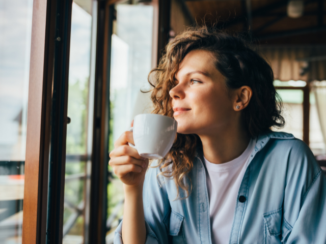 woman sipping coffee next to a window