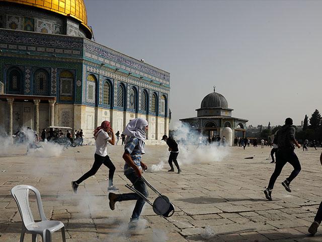 Palestinians run away from tear gas during clashes with Israeli security forces at the Al Aqsa Mosque compound in Jerusalem&#039;s Old City Monday, May 10, 202. (AP Photo/Mahmoud Illean)