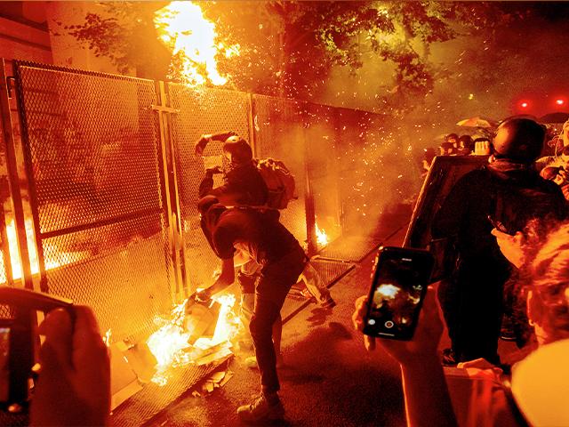 Protesters throw flaming debris over a fence at the Mark O. Hatfield US Courthouse on July 22, 2020, in Portland, Ore. following a larger Black Lives Matter Rally (AP Photo/Noah Berger)