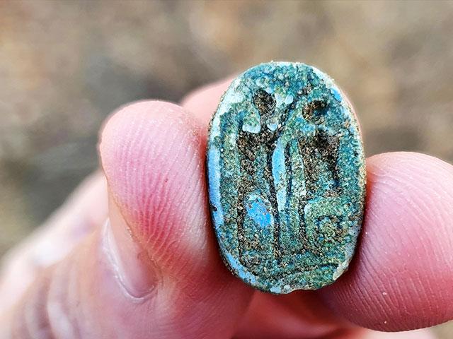 The scarab, showing a seated figure on the right and a standing figure with a raised arm on the left, possibly symbolizing the imparting of authority. Photo: Gilad Stern, Israel Antiquities Authority.
