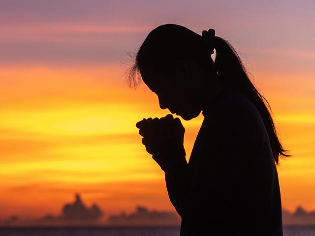 silhouette of a woman crying and praying
