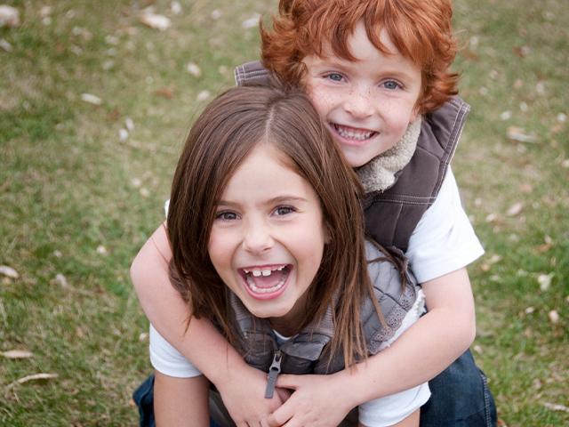 sister giving little brother a piggyback ride