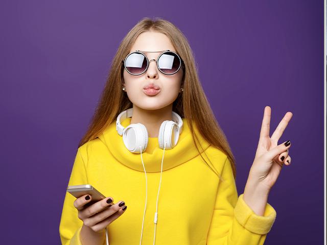 teen girl wearing earphones and giving the peace sign