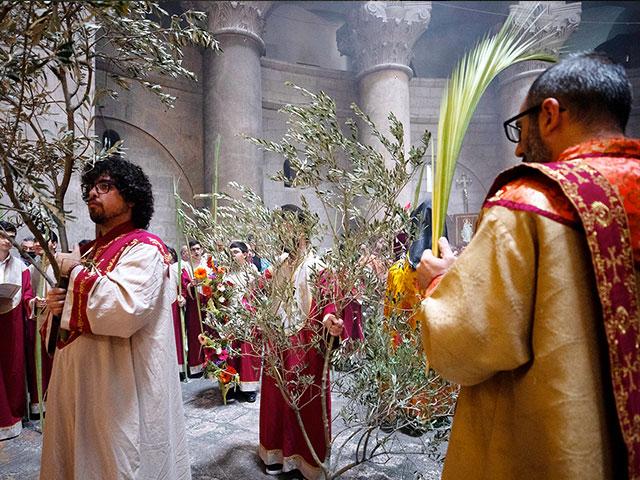 Armenian clergy hold olive tree branches and palm fronds during the Palm Sunday procession at the Church of the Holy Sepulchre. (AP Photo/Oded Balilty)