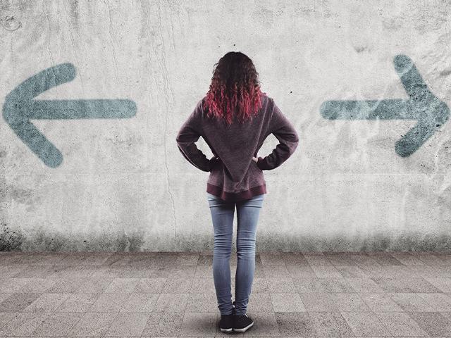woman facing a wall with two arrows pointing in opposite directions