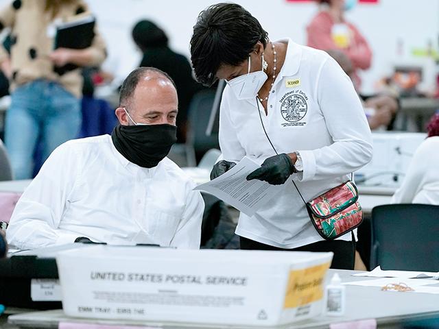A worker checks with an election supervisor at the central counting board, Wednesday, Nov. 4, 2020, in Detroit. (AP Photo/Carlos Osorio)
