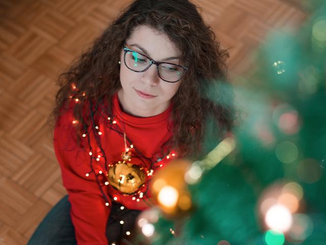 woman sitting beside Christmas tree looking lonely