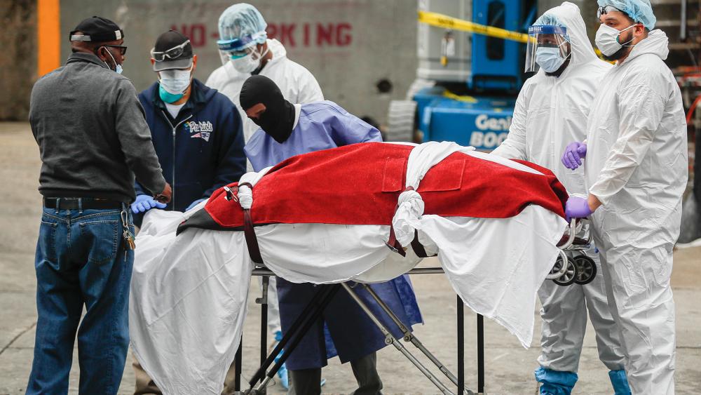 A body wrapped in plastic that was unloaded from a refrigerated truck is handled by medical workers wearing personal protective equipment due to COVID-19 concerns, Tuesday, March 31, 2020, at Brooklyn Hospital Center in New York. (AP Photo/John Minchillo)