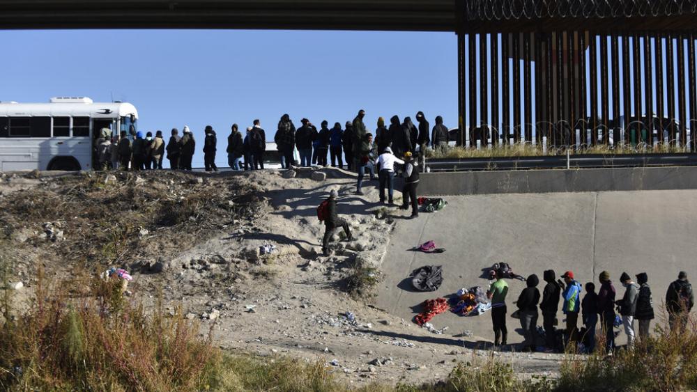 Migrants wait to get into a U.S. government bus after crossing the border from Ciudad Juarez, Mexico, to El Paso, Texas, Dec. 12, 2022. (AP Photo/Christian Chavez)