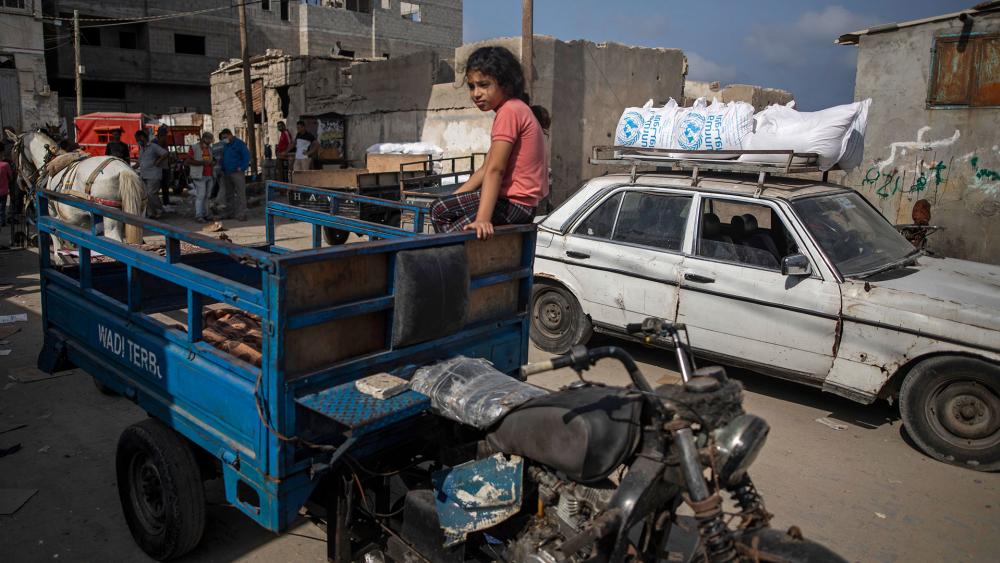 A Palestinian girl sits on an auto rickshaw next to a car loaded with sacks of flour received from UNRWA at a warehouse in Gaza City, Wednesday, Sept. 30, 2020. (AP Photo/Khalil Hamra)