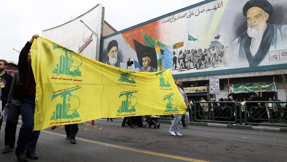 Iranian Muslims carry a banner with flags of Lebanese militant group Hezbollah at pro-Palestinian rally in Tehran, Iran, Friday, Oct. 13, 2023.