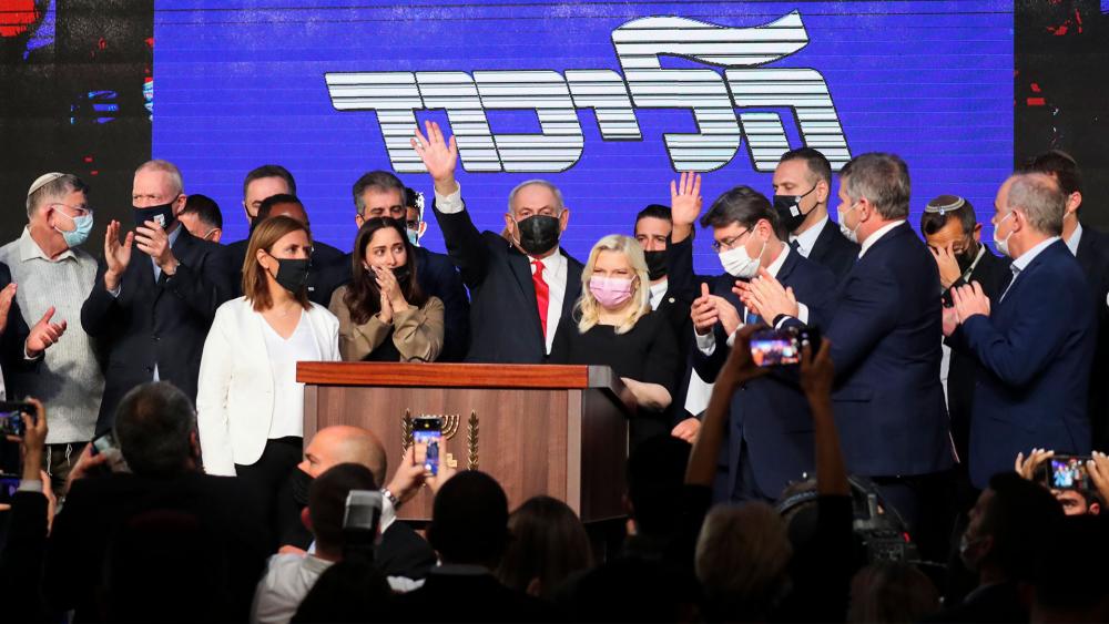 Israeli Prime Minister Benjamin Netanyahu, center,  waves after delivering a speech to supporters following the announcement of exit polls of the Israeli elections. Wednesday, March. 24, 2021. (AP Photo/Ariel Schalit)